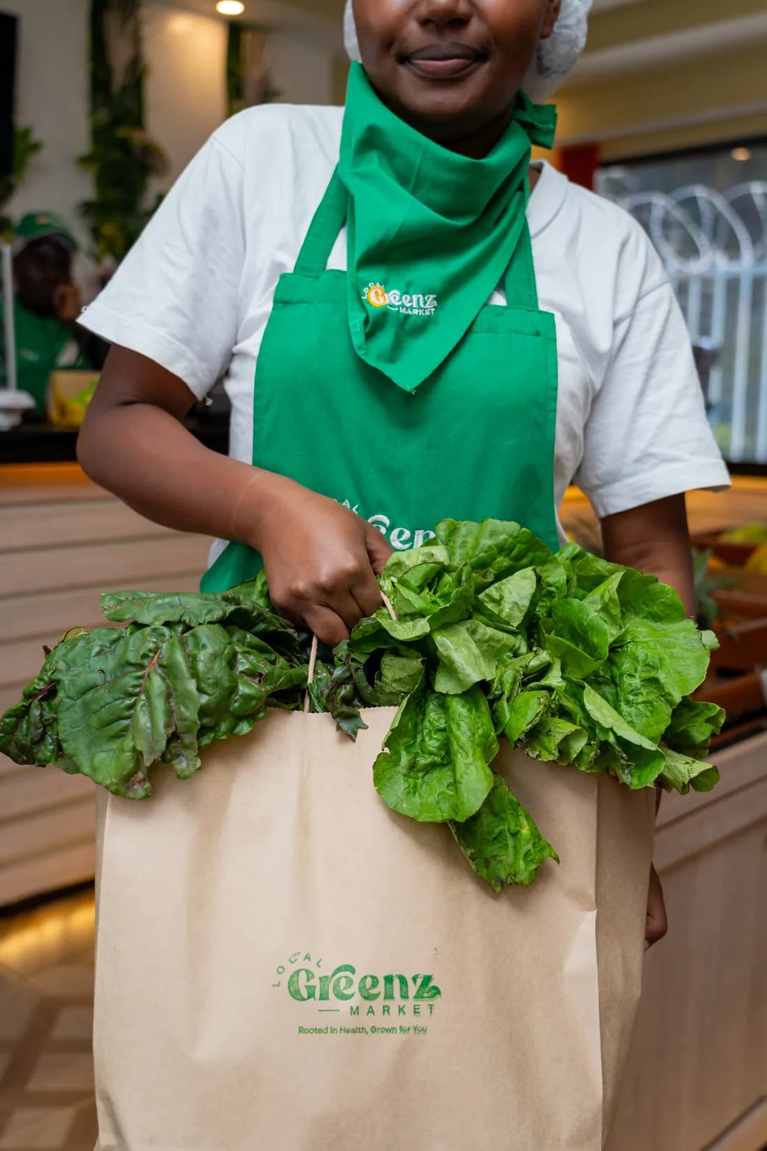 A Local Greenz team member packing chard and lettuce into a branded paper bag